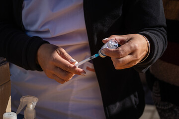 Closeup of a nurse's hand loading a syringe with a vaccine