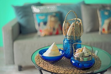 Marine style in the apartment interior - a sofa with pillows and a table with shells and fish figures.