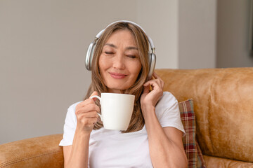 Woman enjoys warm beverage while listening to music in a cozy living room setting during daytime