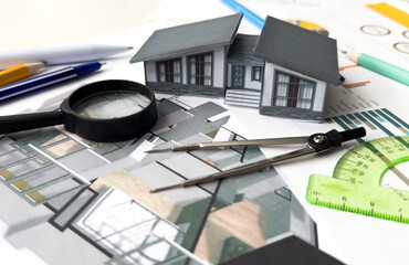 architectural model of houses on desk with drawing technical tools and blueprint rolls, isolated on white background, for building construction plan, interior designer and architect work concept