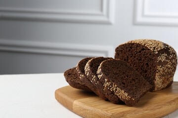 Pieces of fresh rye bread with seeds on white table against light grey wall, closeup. Space for text