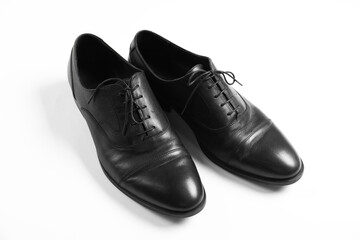 Pair of black leather shoes on white background