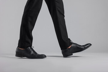 Man wearing pair of black leather shoes on light background, closeup