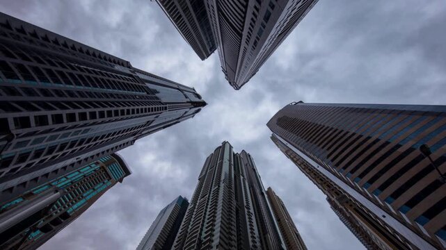 Time-lapse of skyscraper buildings in business district. sunny day and blue sky. Low angle view, zoom out. Asia financial economy, merger  acquisition, or modern architecture concept