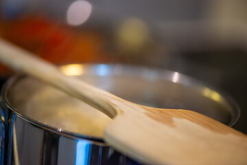A candid kitchen scene showing a woman preparing rice, as boiling water steams from the pot