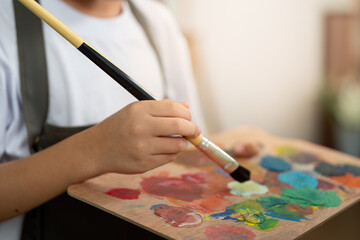 Art Supplies. Close-up of child's hand holding paintbrush and palette.