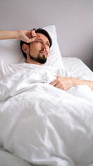 Portrait of a young brunette man sleeping soundly in a soft, cozy bed bathed in early morning light