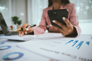 Businesswoman analyzing financial data using calculator, holding documents surrounded by charts,...