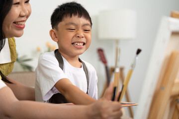 Joyful Art Session. Mother and son sharing painting tools with smiles.