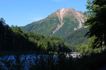 上高地の焼岳と清流に朝霧が漂う幻想的な夏の自然風景

