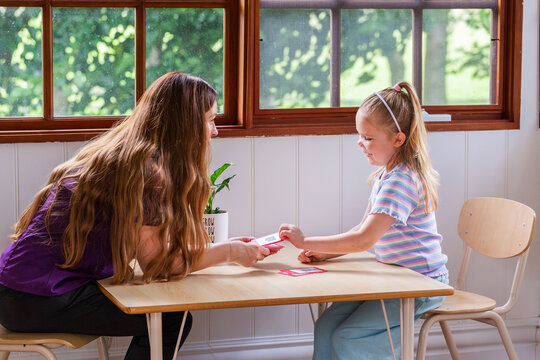 Speech pathologist working with young girl using word flash cards for language development
