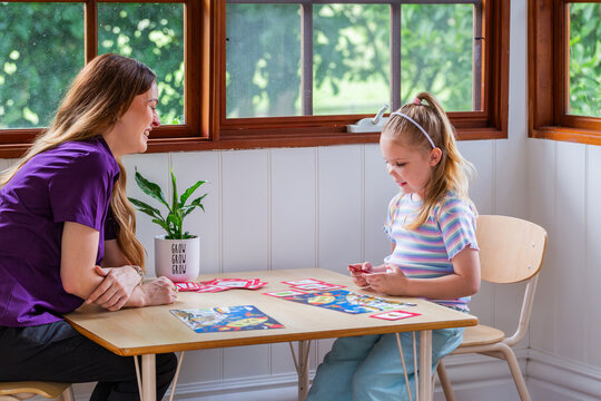 Child with speech disability looking at sound cards talking with speech-language pathologist
