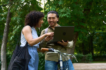 Students sharing laptop next to bicycle in park