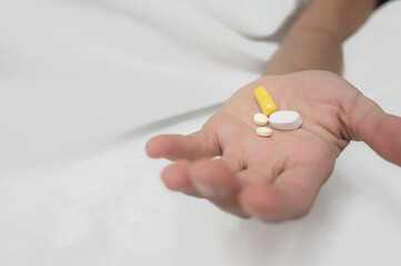 Close-up of a patient holding various pills, symbolizing medication, healthcare, and treatment