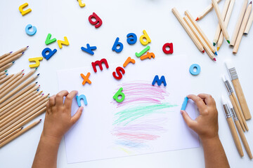 Child engaged in creative alphabet learning with colorful letters and crayons
