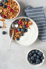 Greek yogurt with granola and berries topping served in a bowl, top view copy space