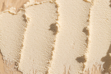 Smears of cosmetic exfoliating scrub on beige background, top view.