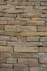 Natural sandstone wall texture with irregular horizontal layers and warm earthy tones. Rough stacked stone surface ideal for architectural backgrounds and 3D materials.