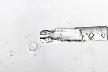 Pipette with serum, hyaluronic acid, peptide, transparent beauty texture close-up.