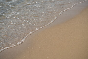 sea waves rolling on sandy beach – close-up shoreline  sea waves gently rolling onto the sandy beach. clear water, foam, and soft motion create a calming natural seascape. ideal for vacation 