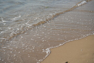 sea waves rolling on sandy beach – close-up shoreline  sea waves gently rolling onto the sandy beach. clear water, foam, and soft motion create a calming natural seascape. ideal for vacation 