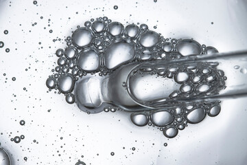 Dropper with bubbles close-up top view, beauty background with cosmetic product.