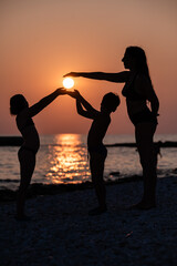 Family playing with sun on beach at sunset