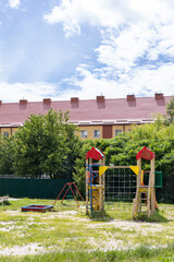 Colorful outdoor playground with climbing frame and sandbox on green grass near residential buildings.