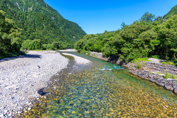 上高地明神橋の下を流れる透明な梓川と夏の山々

