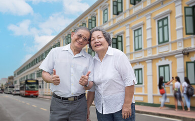 lderly tourist couple smiling, posing outdoors amidst stunning architecture on a bright, sunny day