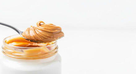 A spoonful of creamy peanut butter lifted from a jar isolated on white background