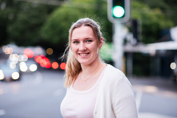 A 24 year old woman with a ponytail in an urban setting at dusk