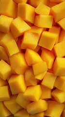 Close-up shot of numerous uniformly cut, vibrant yellow mango cubes filling the frame, showcasing their juicy texture and rich color