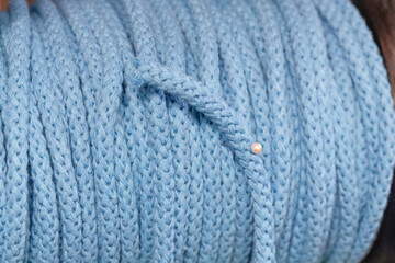 Soft blue knitted fabric with intricate texture and delicate pearl detail for creative projects