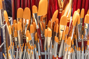 Collection of artist paintbrushes with orange bristles arranged in a vibrant display for creative...