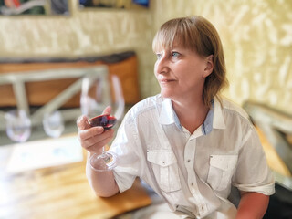 Woman enjoying a glass of red wine while relaxing in a cozy cafe with warm lighting and rustic decor