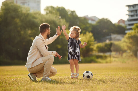 Giving high five, teamwork. Father with his little daughter are on the field