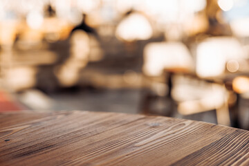 Close-up of a wooden table surface with a blurred background. The wood has a rich texture and warm...