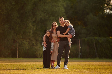 The family of husband, wife and two daughters on the field outdoors