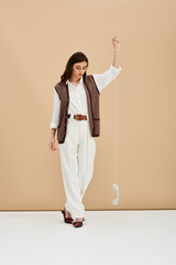 Stylish young woman with long brown hair showcases modern fashion in studio setting