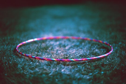 Colorful hula hoop resting on grassy surface at twilight, inviting playful outdoor activities