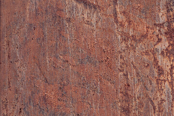Close-up of a textured rusty metal surface with shades of brown and orange. The surface shows signs of wear and corrosion, creating an industrial aesthetic.