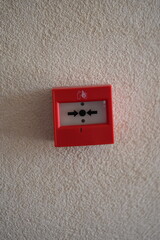Red fire alarm button on white wall. Emergency safety equipment for building security and fire prevention concepts