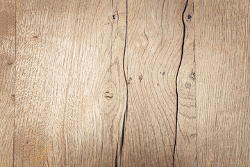 Close-up of a textured wooden surface with natural grain patterns. The wood is light-colored with visible knots and lines