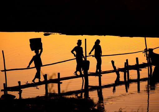 Women crossing a brige at sunset in Bagan, Myanmar