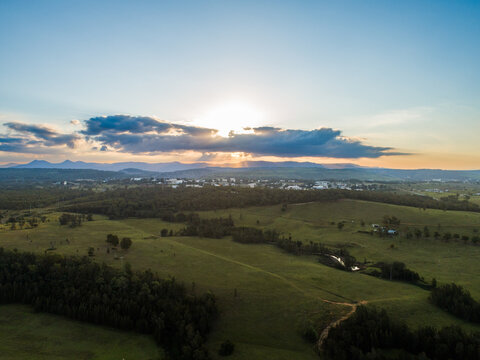 Sunrays streaming from behind clouds on horizon in rural Hunter Valley landscape seen from aerial vi
