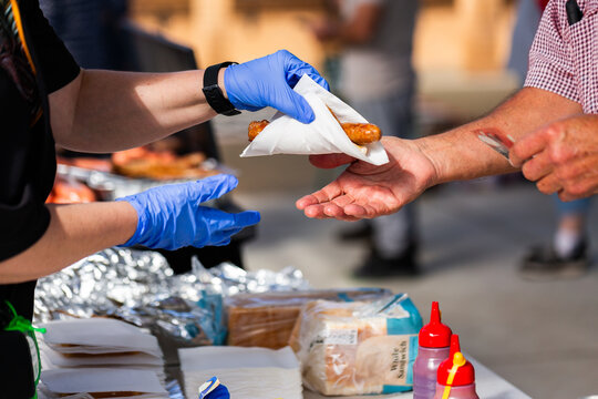 Handing a voter a democracy sausage in serviette on election day