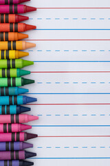 Crayons with ruled loose leaf notebook paper background