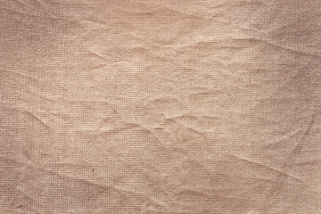 A close-up view of textured fabric with a soft, beige color. The surface shows subtle wrinkles and...
