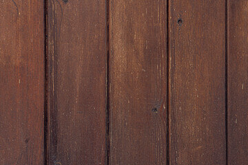 Close-up of a rustic wooden surface with dark brown planks. The texture shows natural grain...
